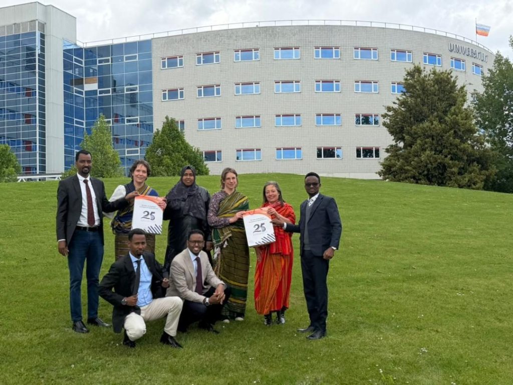 Consortium delegates holding commemorative materials outside a European partner university building