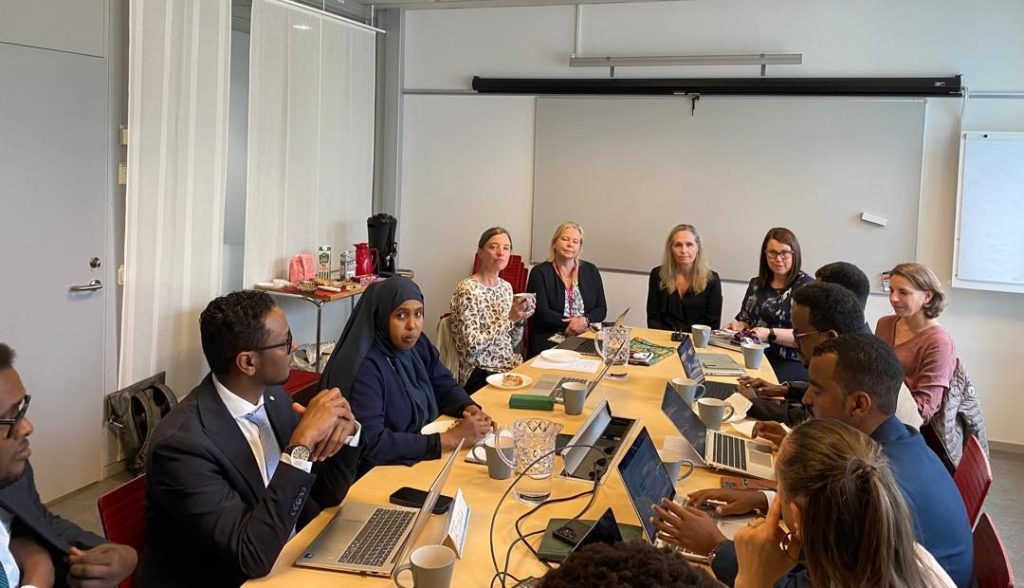 Somali and European consortium members working together around a table with laptops during a CURIOUS project session
